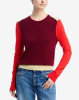 Person wearing a red and burgundy sweater with cut-out shoulders on a white background