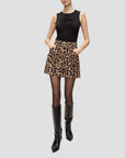 Person wearing a black sleeveless top and leopard print skirt with black knee-high boots on a white background