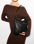 Model wearing MZ Wallace Crosby Sienna Black Hobo & Shoulder bag, and brown long sleeve dress in front of a white background.
