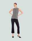 Woman wearing a black and white striped sleeveless top and black pants on a white background
