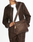 person wearing a brown tracksuit and white tee wearing the mz Wallace Metro Flat Crossbody Walnut on a white background