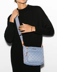 model wearing all black and the mz wallace Metro Scout Crossbody Deluxe Stone Blue on a grey background