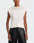 White sleeveless sweater with bead embellishments worn by a model on a white background