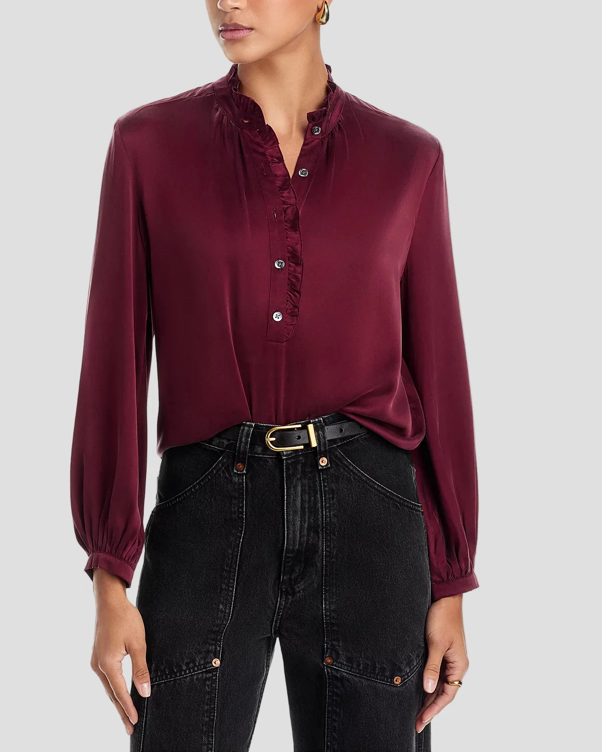 Woman wearing a burgundy blouse and black jeans on a white background