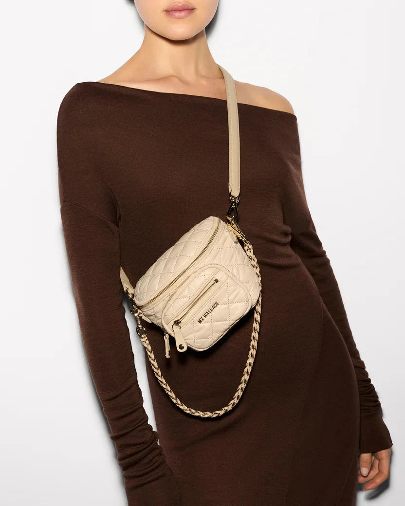 MZ Wallace Micro Crosby Sling Buff Crossbody worn by model wearing a brown off the shoulder dress in front of white background.