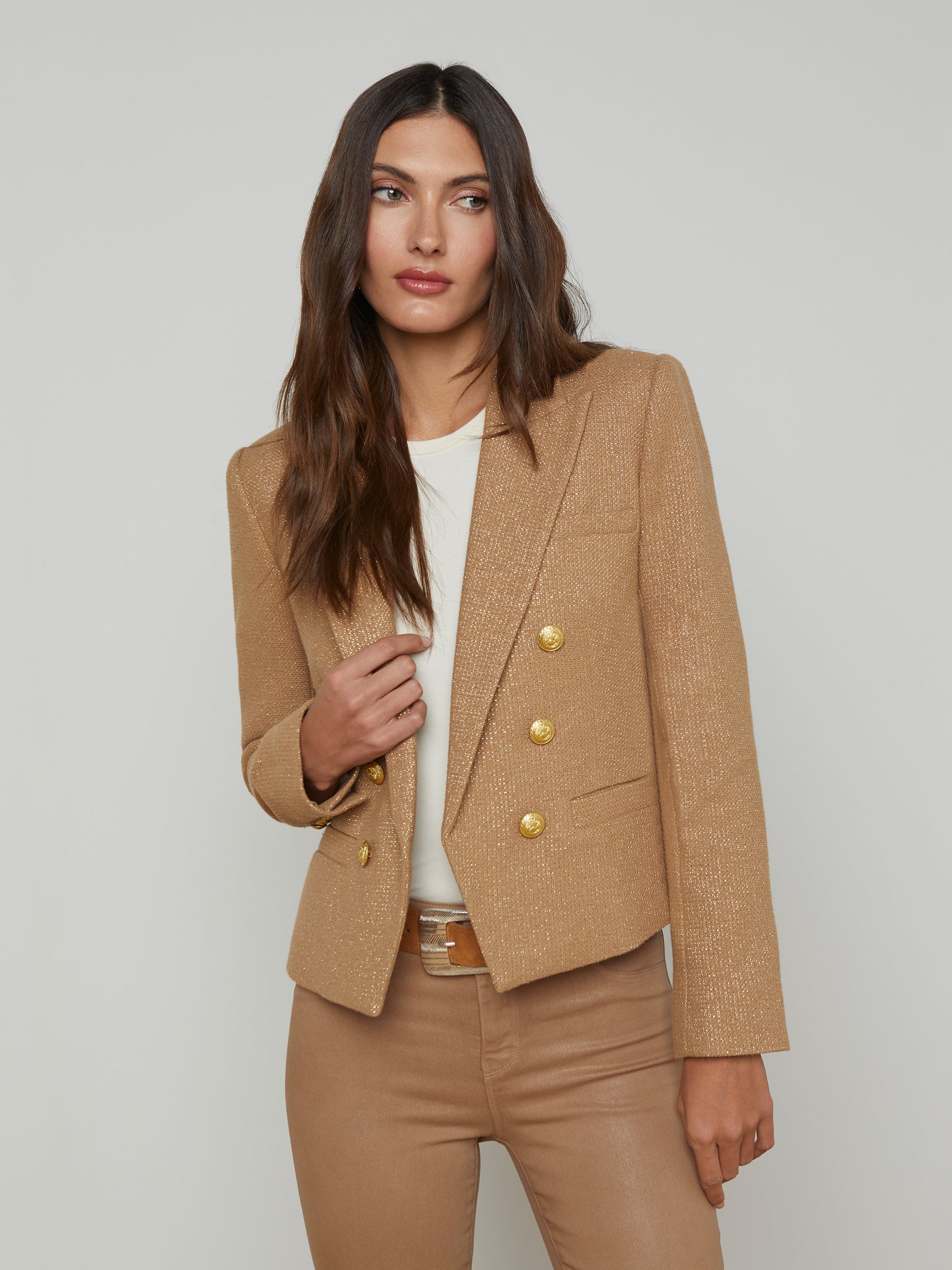 front upper half view of a brunette model wearing the l'agency Brooke double breasted crop blazer in latte/gold with tan pants and a brown belt