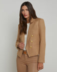 front upper half view of a brunette model wearing the l'agency Brooke double breasted crop blazer in latte/gold with tan pants and a brown belt