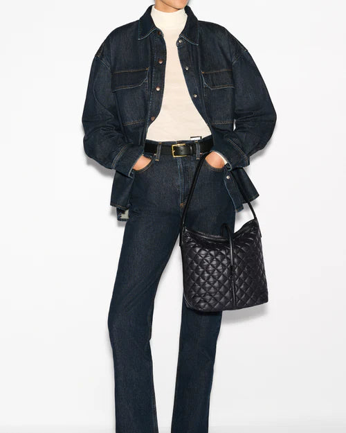 model wearing a white turtleneck, denim jacket, jeans, and a black belt and holding the mz wallace Small Astor Hobo Black on a grey background