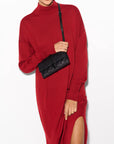 model wearing a red dress wearing the mz wallace Astor Convertible Crossbody Black on a grey background 