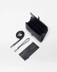 top view of the mz wallace Astor Convertible Crossbody Black on a grey background  with the straps and interior wallet laid out