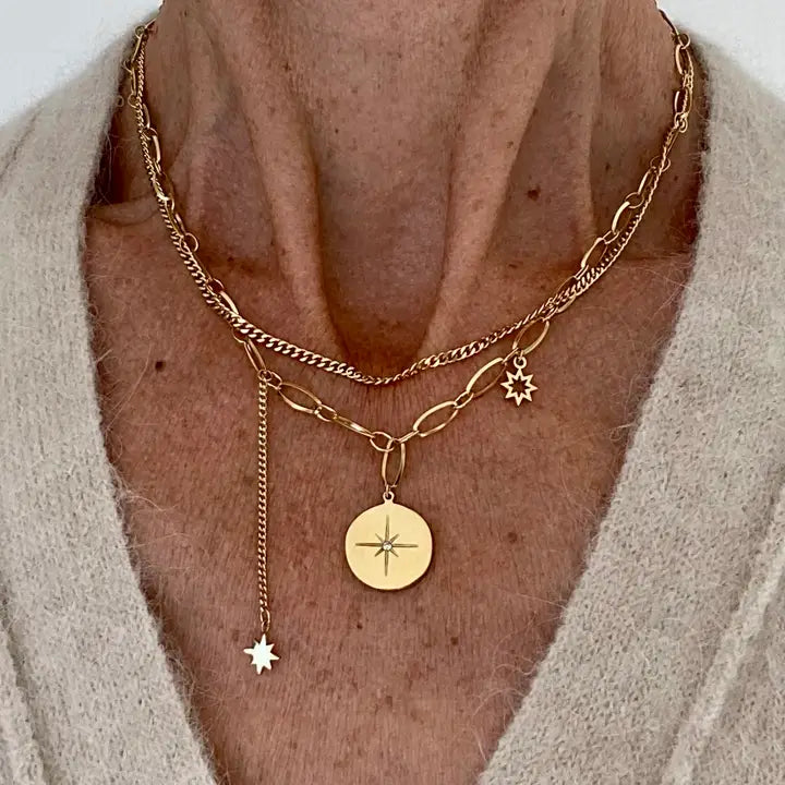 close up of the Ma Cocotte Cosmos Necklace on a lady's neck wearing a cream v-neck sweater