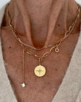 close up of the Ma Cocotte Cosmos Necklace on a lady's neck wearing a cream v-neck sweater