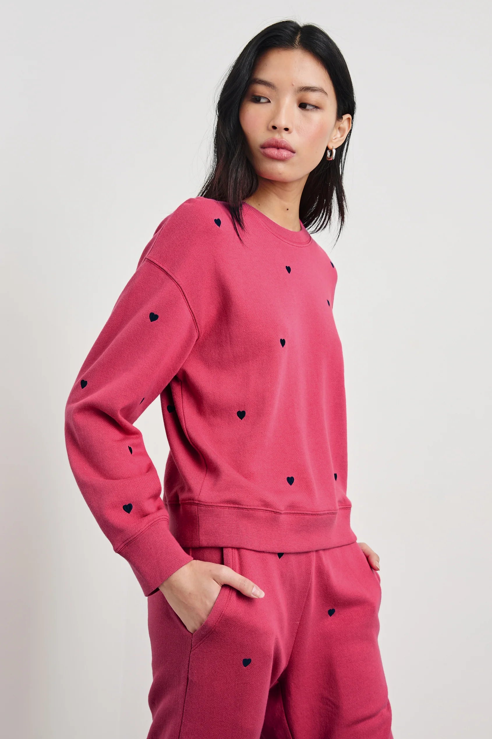 side view of the upper half of a brunette model with the rails ramona sweatshirt in pink midnight hearts with matching kingston pants