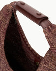 close up view of the handle of the Staud Large Raffia Moon Tote Bag in Mahogany with white background