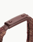 even close view of the handle of the Staud Large Raffia Moon Tote Bag in Mahogany with white background