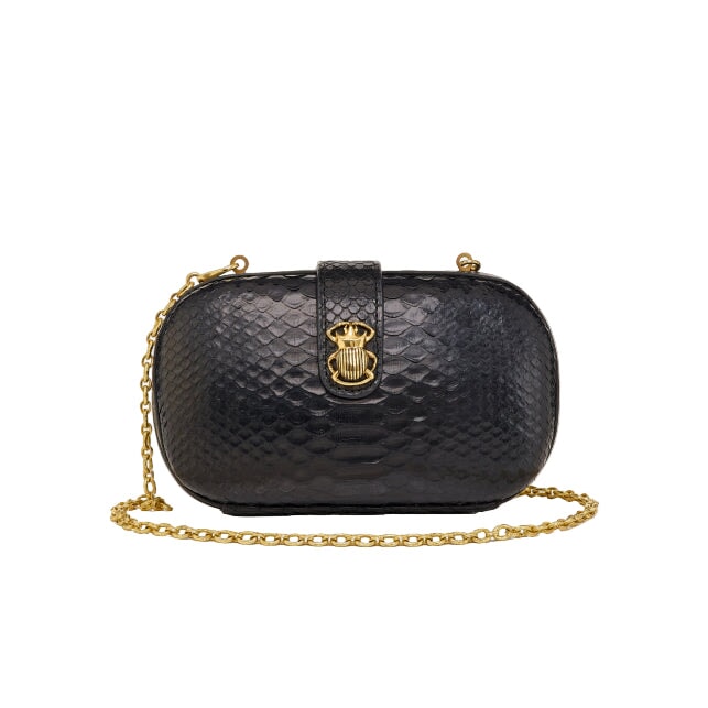 Black textured handbag with gold chain and clasp on a light gray background