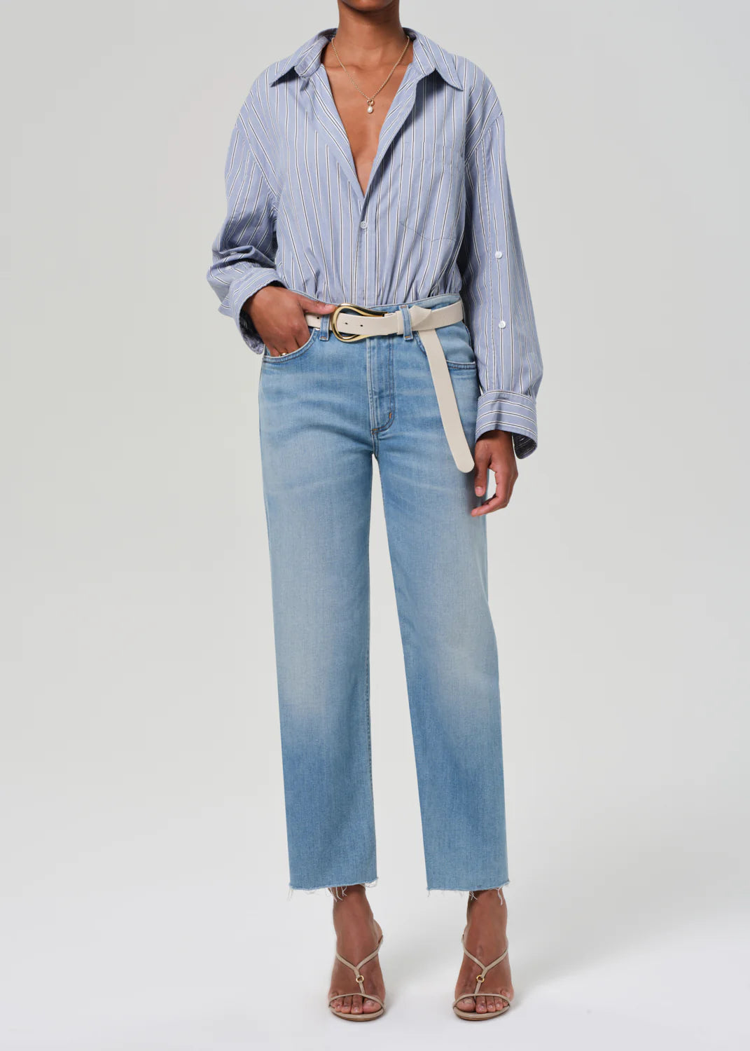 full front view of model wearing the citizens of humanity Palma Straight Lisbon with a white belt, tan sandals, and a blue striped button down on a white background