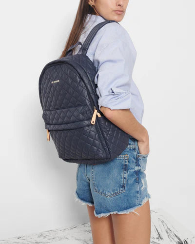 model wearing mz Wallace city metro backpack dawn on white background, denim shorts and a blue button down