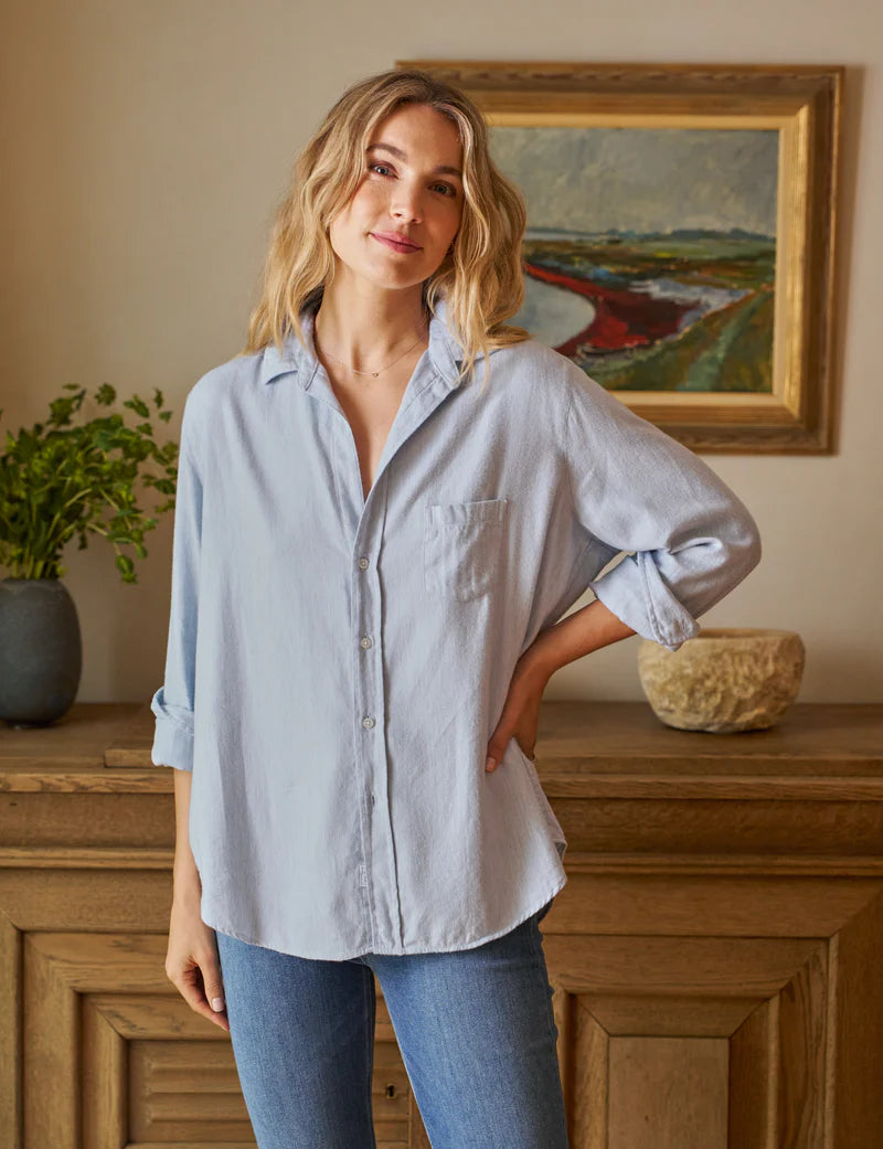 blonde model wearing the frank & eileen Eileen Relaxed Button Up Gray Blue with jeans in front of a console table and art