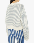 back close up view of brunette girl wearing mother bell sleeve jumper roll in did you make that on a white background with striped blue pants