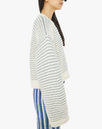 side close up view of brunette girl wearing mother bell sleeve jumper roll in did you make that on a white background with striped blue pants