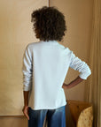 back top half view of a black model wearing the frank & eileen Patrick Popover Henley Triple Fleece Ice and jeans in front of a beige background