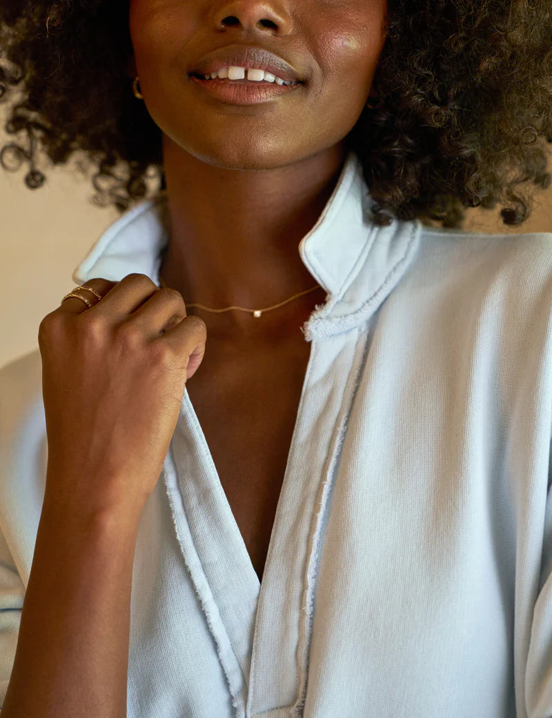 close up view of the collar of a black model wearing the frank & eileen Patrick Popover Henley Triple Fleece Ice in front of a beige background