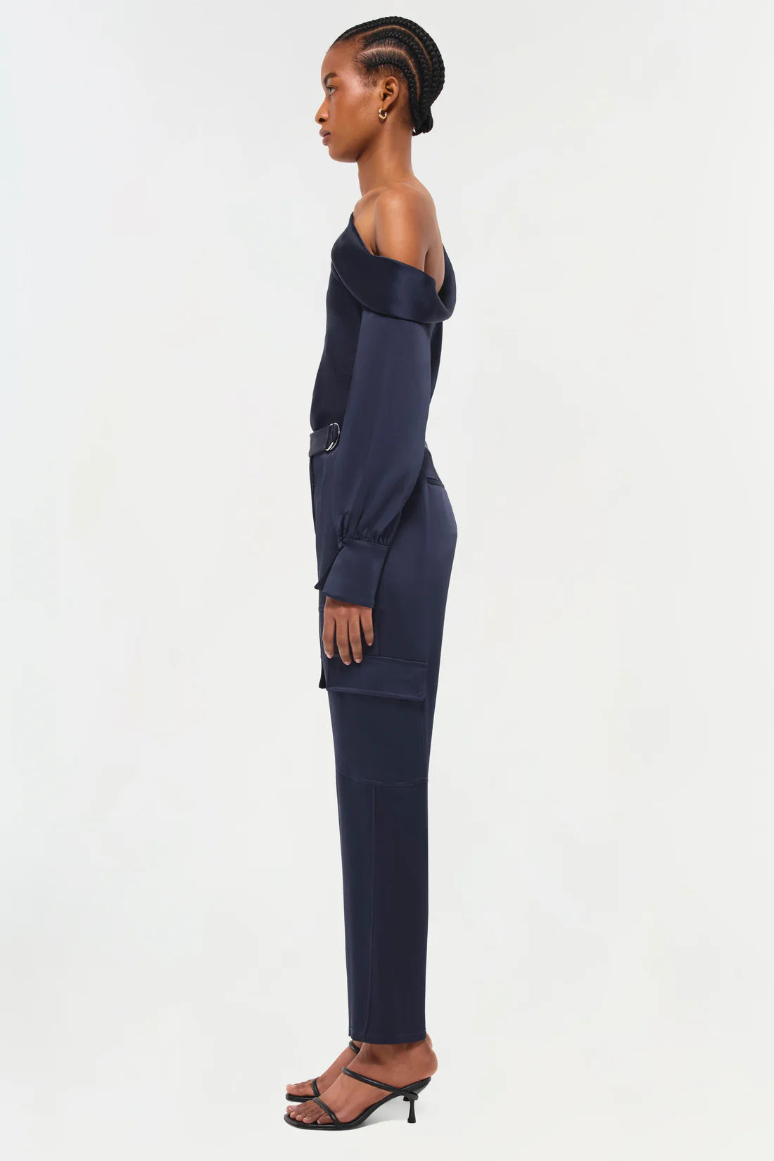 full side view of model on a white background wearing the simkhai Carolina utility pant in midnight with matching blouse and black strappy heels