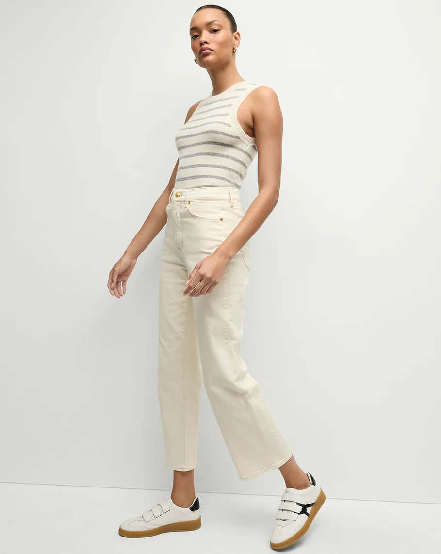 side view of of a model wearing the Veronica Beard ankle high rise straight ecru, a striped tank top, and white sneakers on a white background